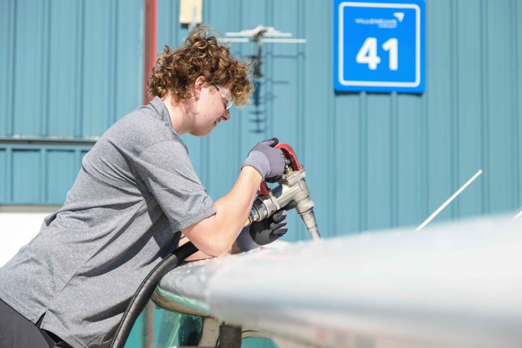 Young man refueling a small aircraft's wing tank at Villeneuve Airport